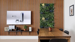 Une pièce moderne avec un mur en lambris de bois, un téléviseur fixé au mur, une table à manger en bois et un jardin vertical.