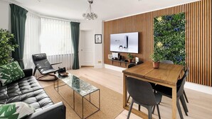 Un salon moderne comprenant un canapé, une table basse, une table à manger avec des chaises, un téléviseur fixé à un mur en bois et un jardin vertical.