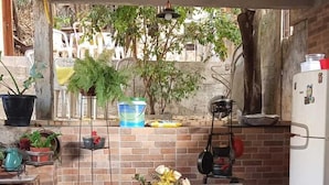 An outdoor dining area with a checkered tablecloth, wooden chairs, and potted plants. - Pousada Plantar e Cuidar (Santa Cruz do Escalvado)