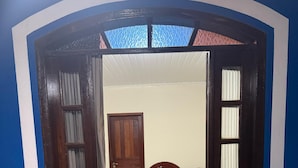 A bedroom with a bed, a door, and a view through an open doorway. - Pousada Plantar e Cuidar (Santa Cruz do Escalvado)