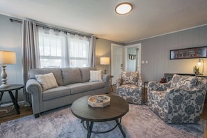 A living room with a grey sofa, patterned armchair, and a coffee table.
