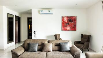 A modern living room with a beige sectional sofa, a brown armchair, and a red abstract painting on the wall.