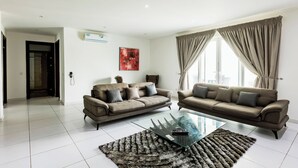 A modern living room with two sofas, a glass coffee table, and a shaggy rug.