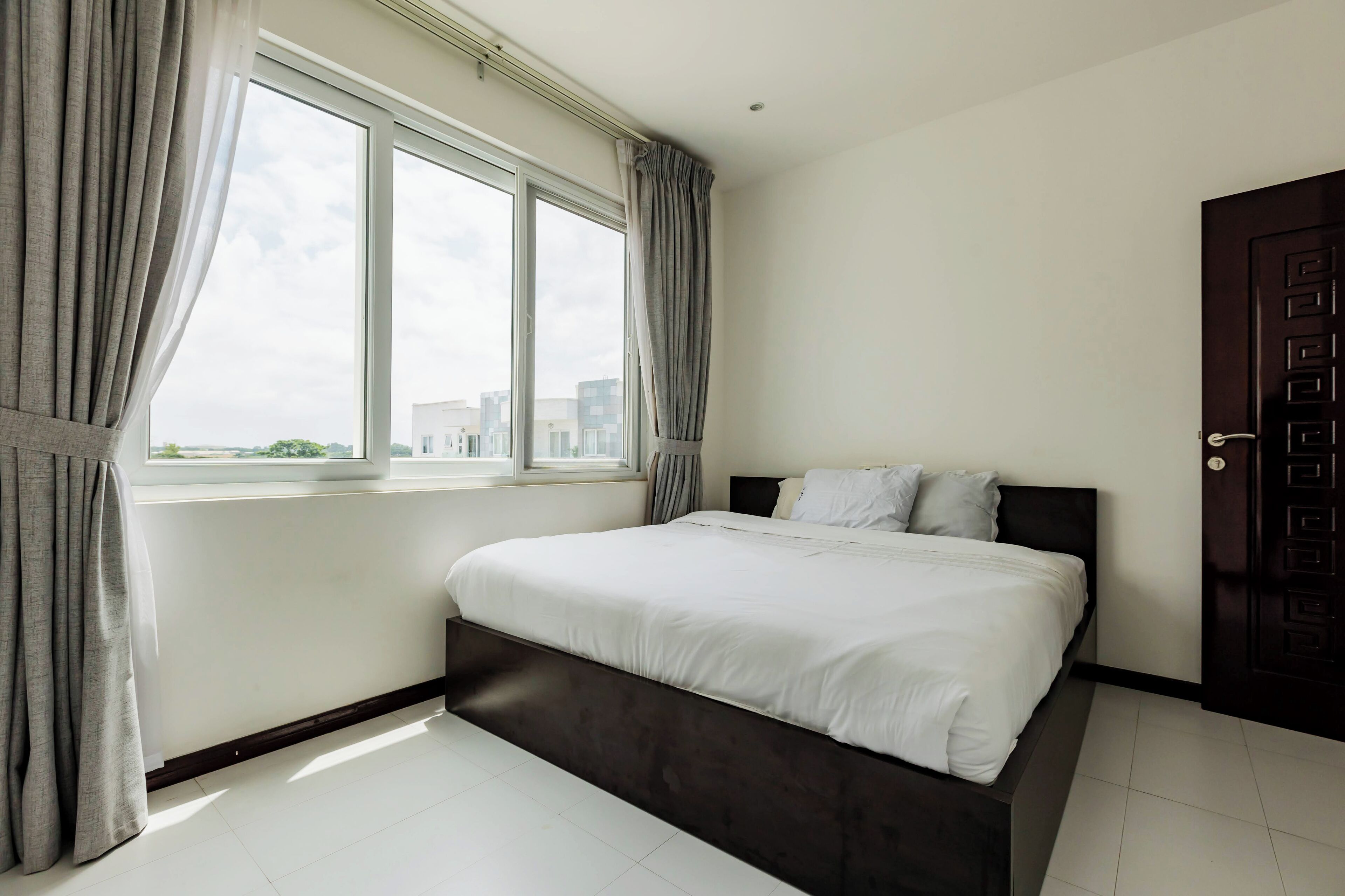 A bedroom with a large window, a bed, and a door.