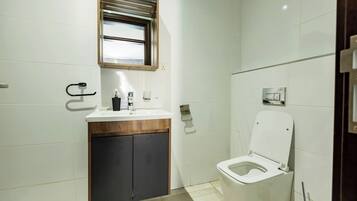 Een moderne badkamer met toilet, wastafel en spiegel.