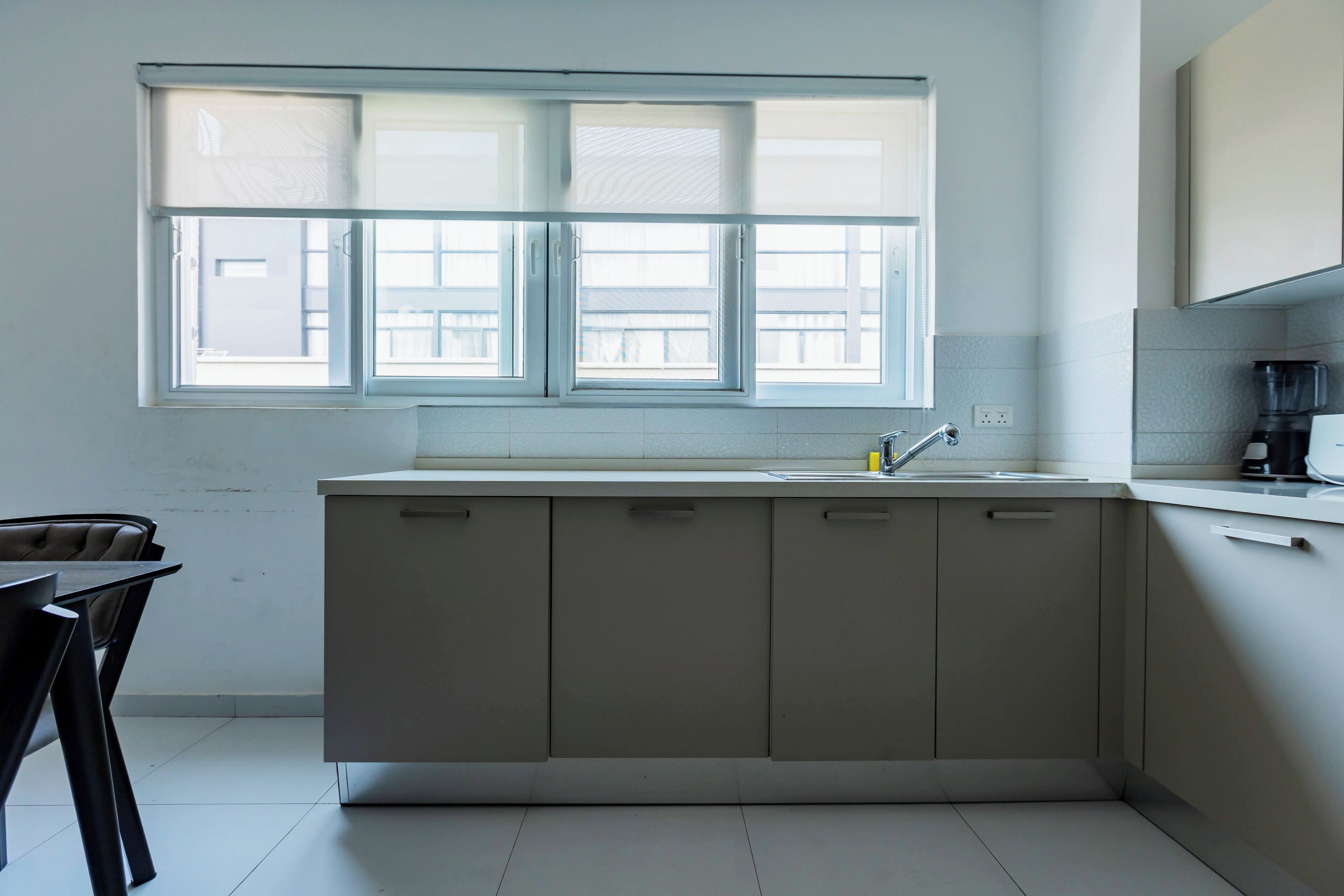 A modern kitchen with a large window, a sink, and cabinets.