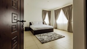 A bedroom with a bed, curtains, a rug, and a wooden door.