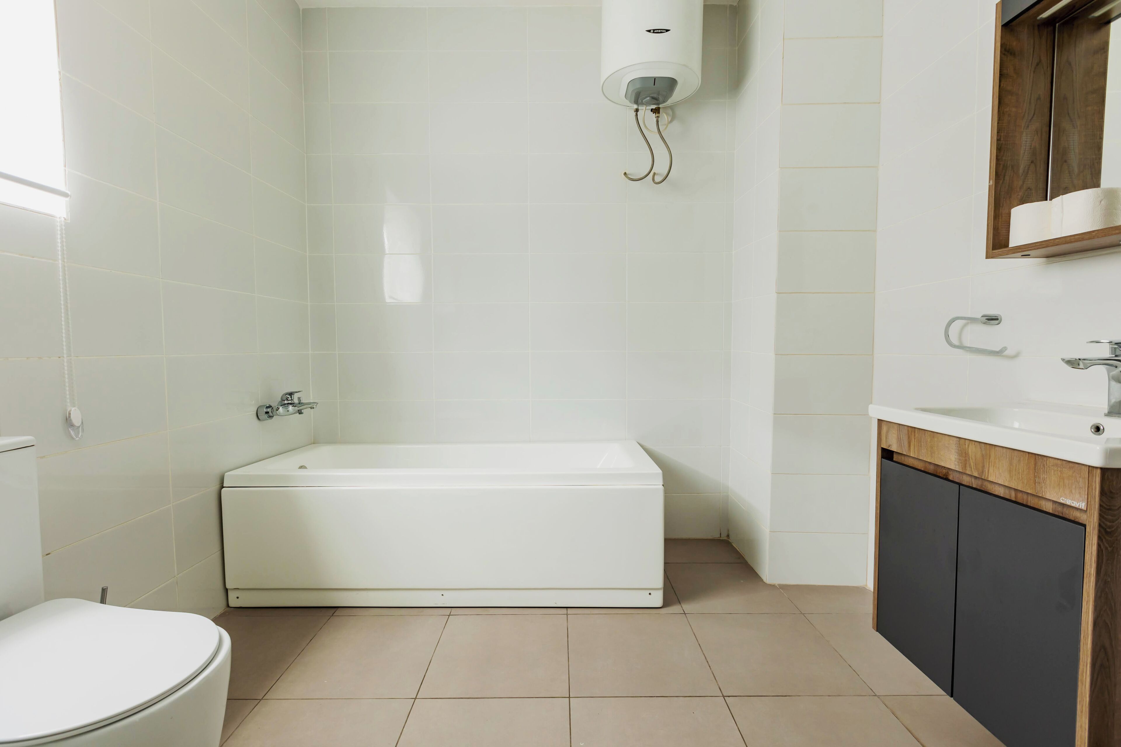 A bathroom with a white bathtub, a toilet, and a sink with a wooden vanity.