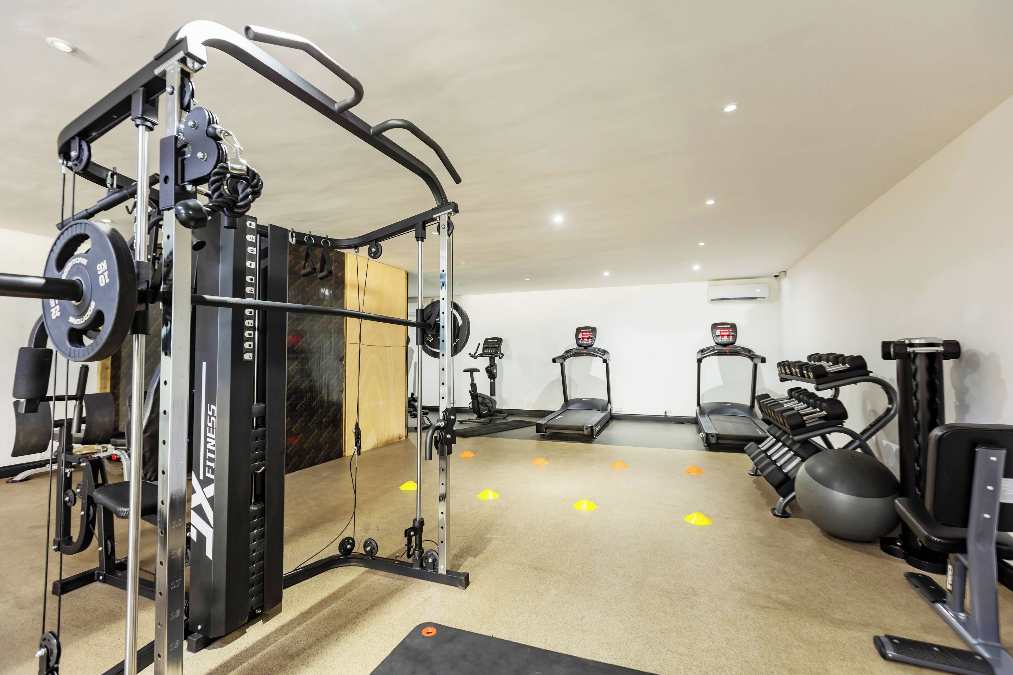 Un gimnasio con equipo de levantamiento de pesas, cintas de correr y pelotas de ejercicio.