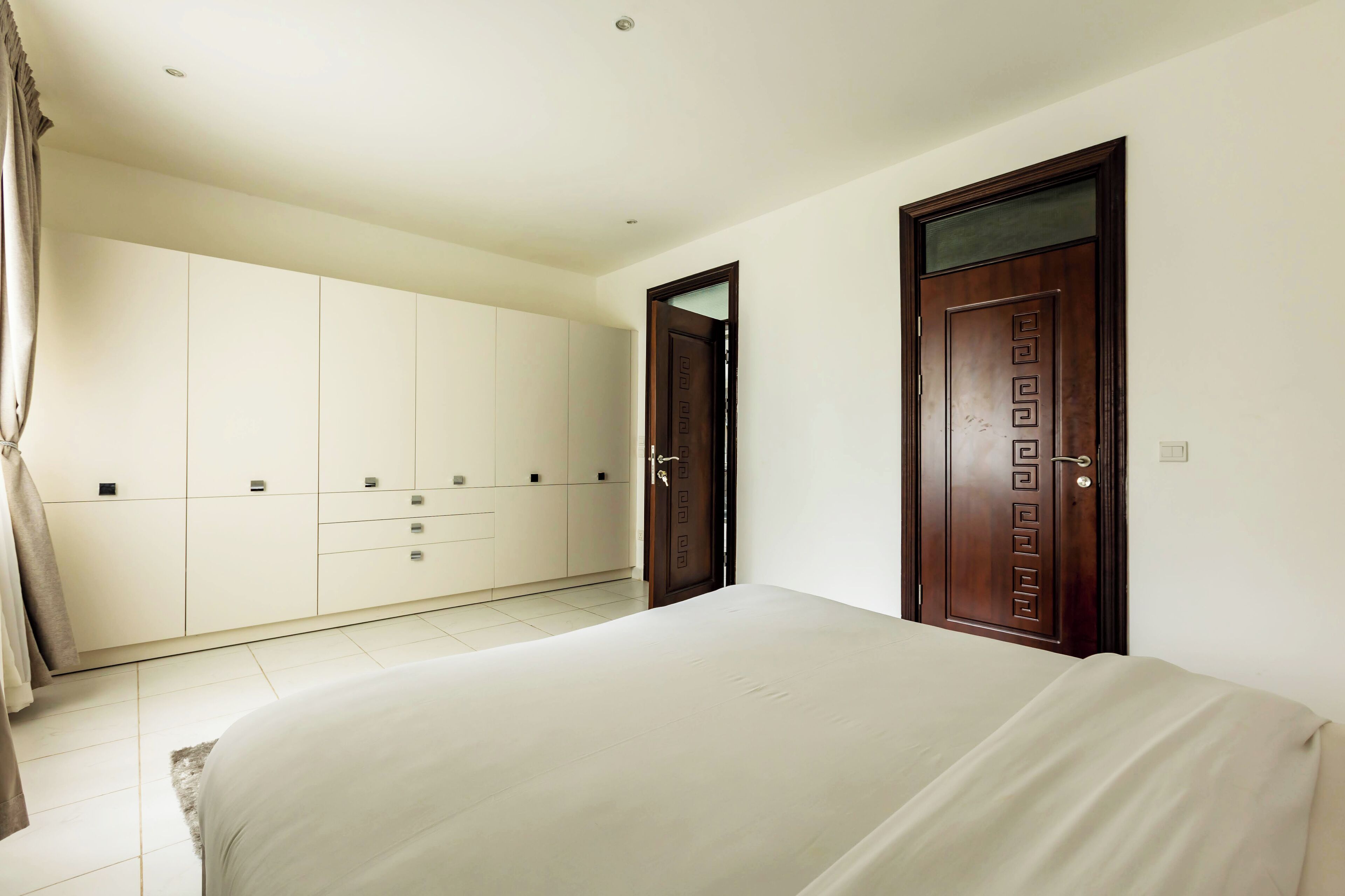 A bedroom with a bed, a wardrobe, and two doors.