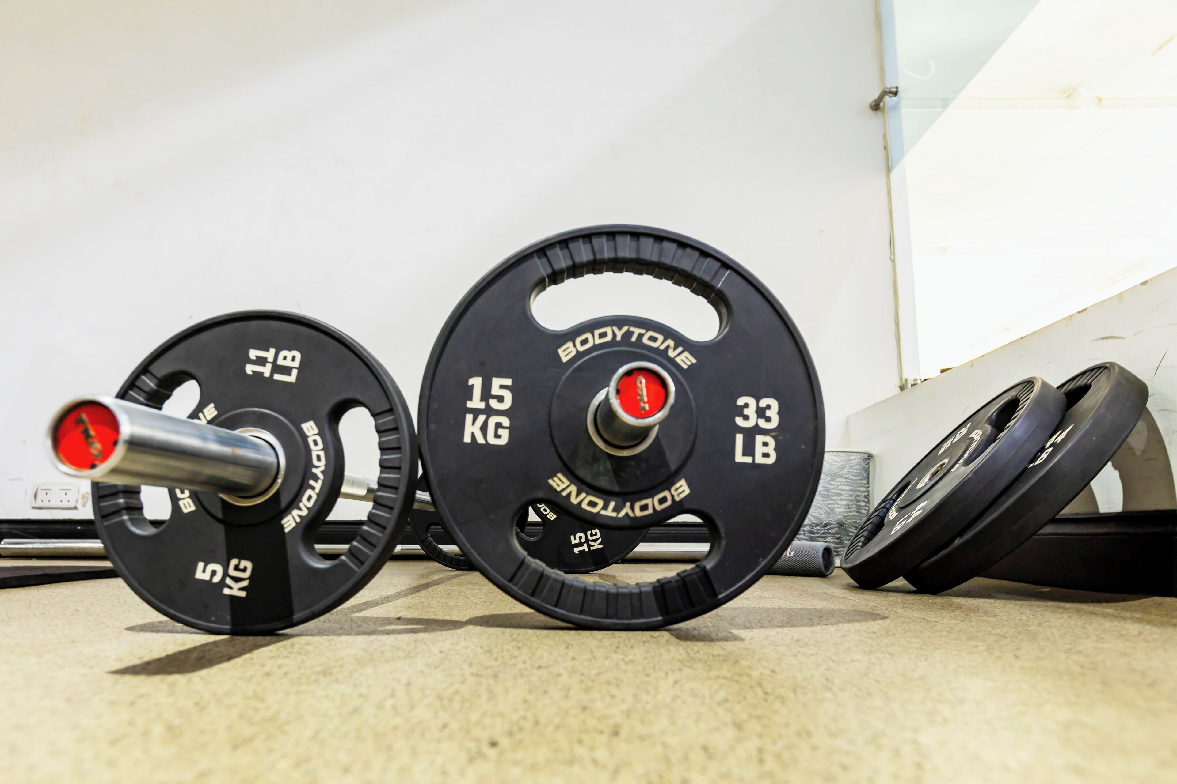 Two weight plates on a floor with a white wall in the background.