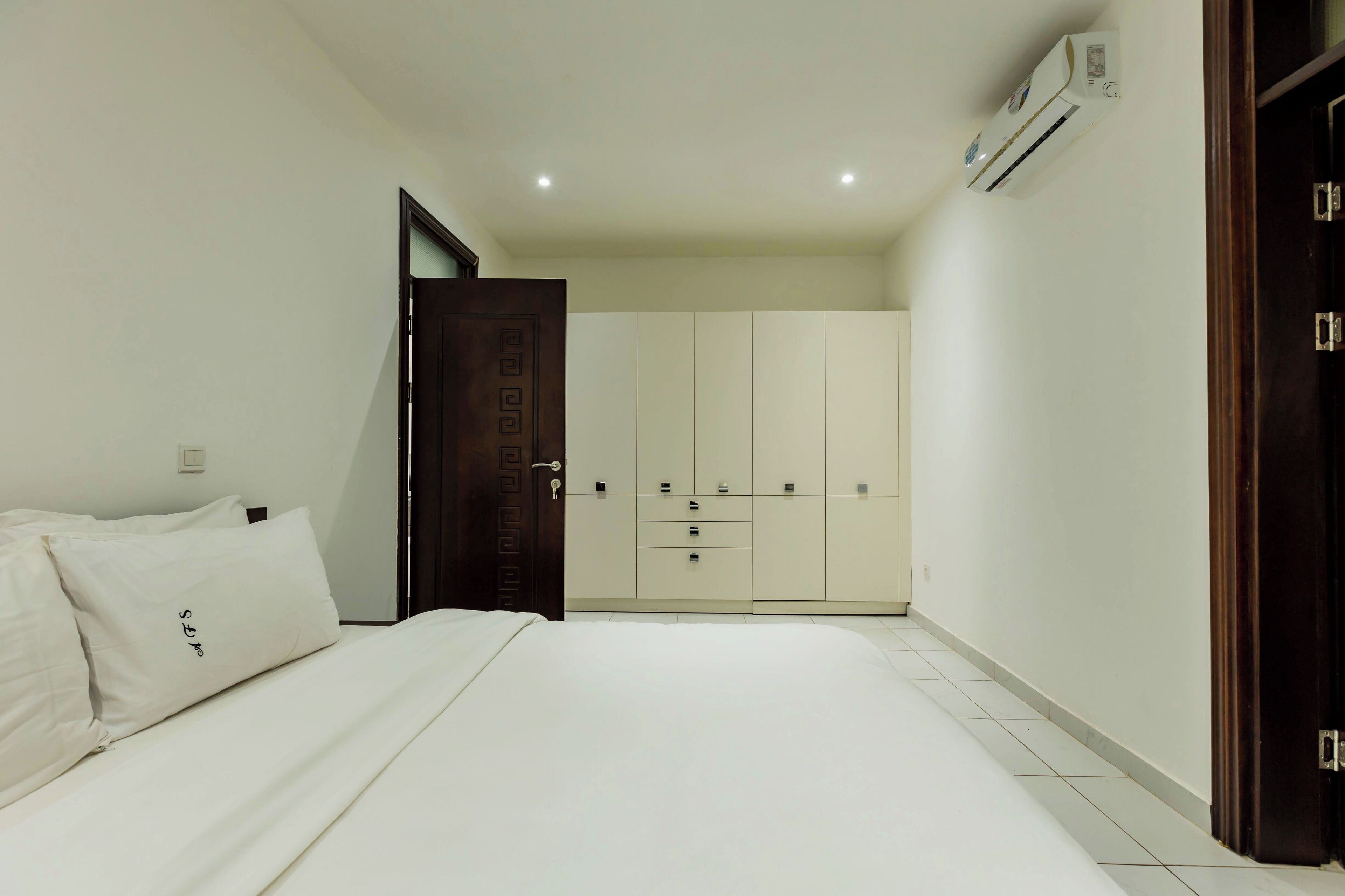 A bedroom with a bed, a wardrobe, and an air conditioning unit.