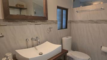 A bathroom with a large sink, toilet, and a mirror.