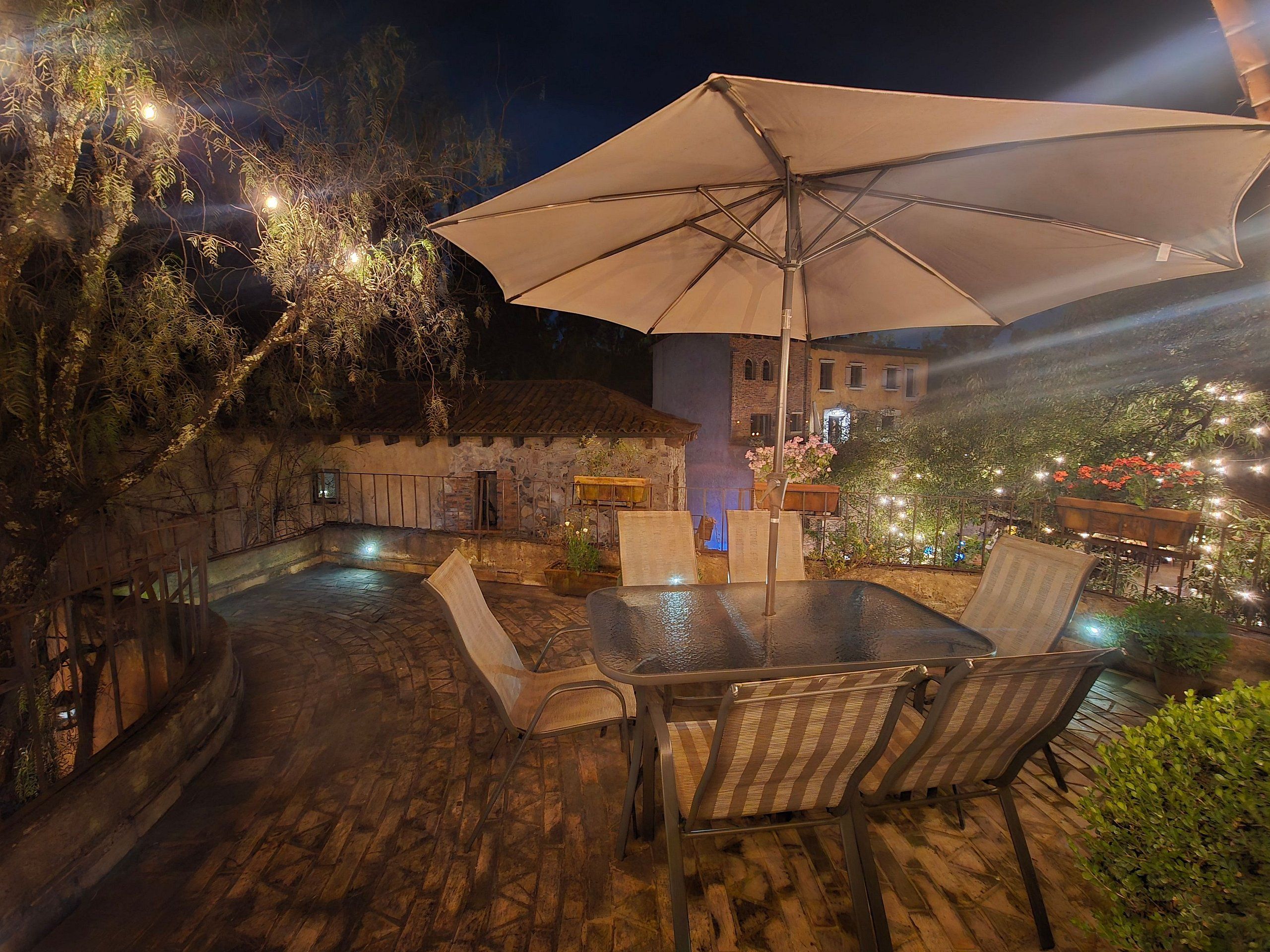An outdoor patio with a table and chairs, an umbrella, and a stone wall.
