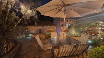 An outdoor patio with a table and chairs, an umbrella, and a stone wall.