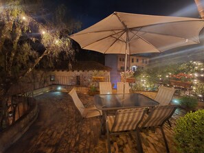An outdoor patio with a table and chairs, an umbrella, and a stone wall.