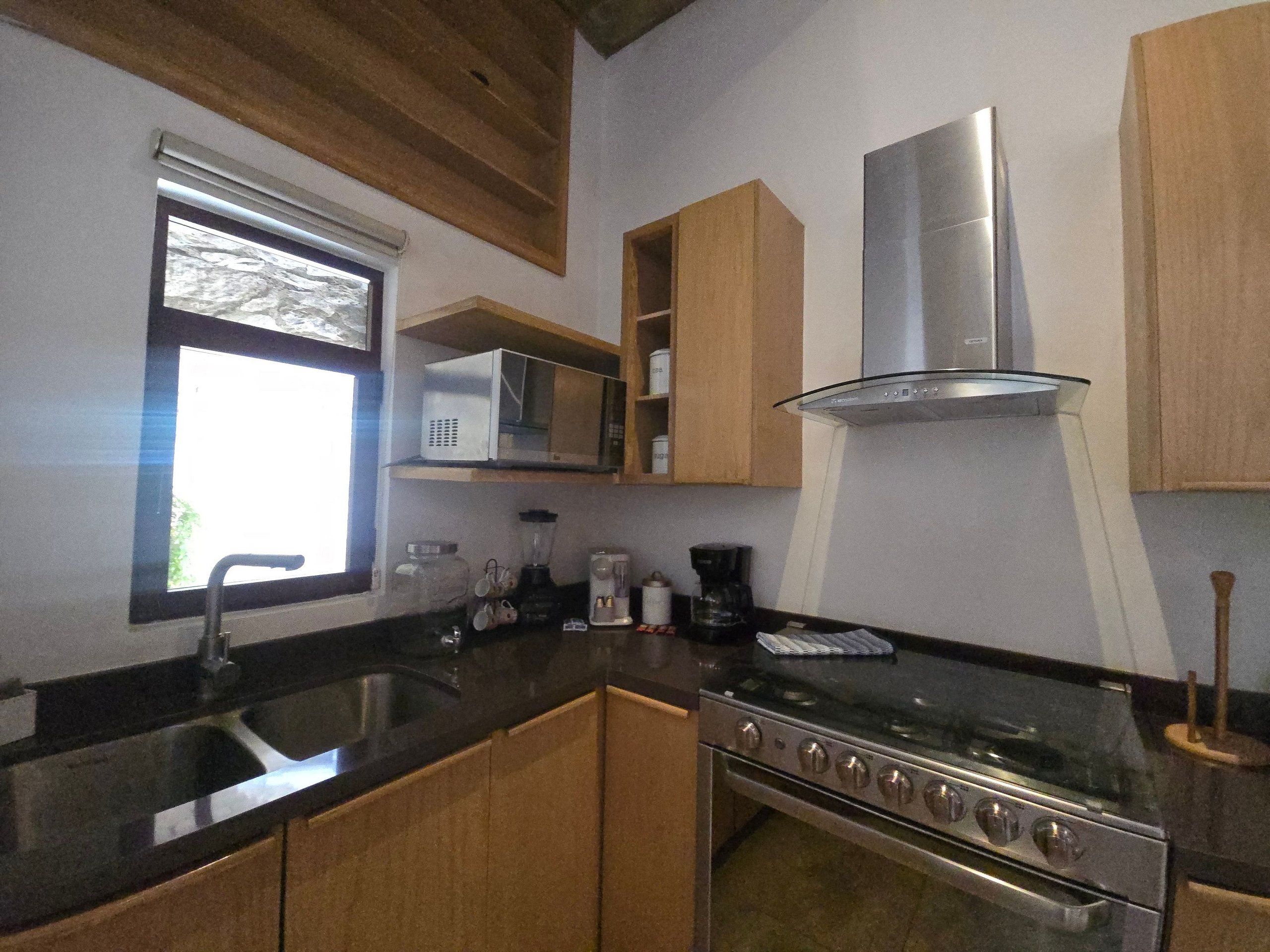 Eine Küche mit Edelstahlherd, einer Mikrowelle und Holzschränken.