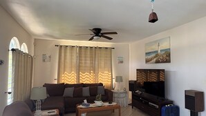 A living room with a sofa, a coffee table, a TV, and a ceiling fan.