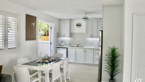 Een moderne keuken met witte kasten, een eettafel met stoelen en een plafondventilator.