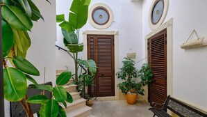 A narrow corridor with a bench, two doors, and potted plants. - A CASA DI BARBARA A love nest in the heart of Galatina (Galatina)