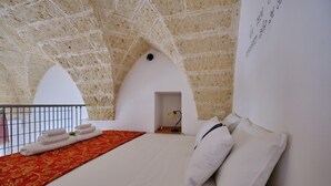 A bedroom with a high, textured ceiling, a bed with white linens, a red patterned bedspread, and a small desk with a lamp. - A CASA DI BARBARA A love nest in the heart of Galatina (Galatina)
