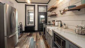 A modern kitchen with a stainless steel refrigerator, a double sink, and wooden flooring. - “Blame Jaime” downtown, the heart of all the fun! (Port Clinton)