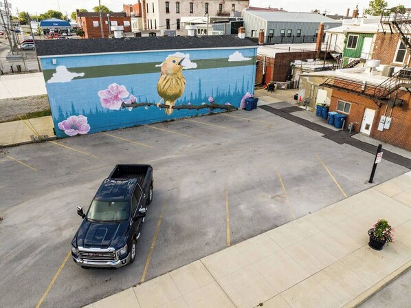 A parking lot with a mural of a bird and flowers on a building wall. - “Blame Jaime” downtown, the heart of all the fun! (Port Clinton)