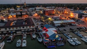 A marina with boats docked, a covered area with tables, and buildings in the background. - “Blame Jaime” downtown, the heart of all the fun! (Port Clinton)