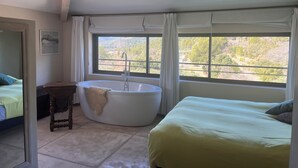 Un dormitorio con un ventanal grande, una bañera y una cama.