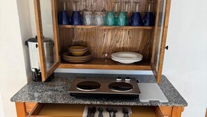 Eine Küche mit Einbauherd, Holzschränken und einer Arbeitsplatte mit Wasserkocher und Besteck.