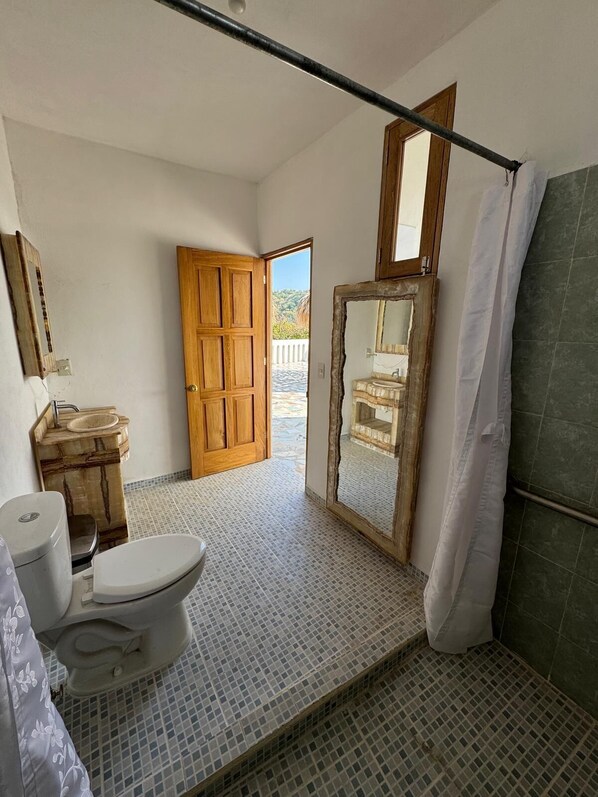 Une salle de bain comprenant des toilettes, un lavabo et un espace douche.