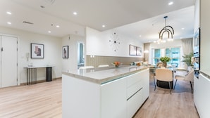 A modern kitchen with a central island, white cabinetry, and a dining area with a table and chairs.