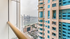 A high-rise building with multiple balconies and a view of a marina and city skyline.