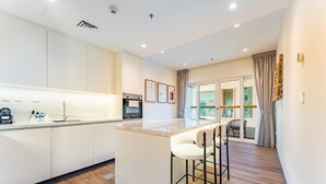 A modern kitchen with a central island, bar stools, and a coffee machine. - Upgraded 2BR with Partial Sea and City Views Near the Beach, Elite Residence (Dubai)