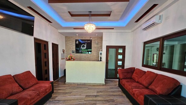 Ein Hotel-Empfangsbereich mit einer Rezeption, zwei roten Sofas, einer Kristallleuchter und Holzboden.