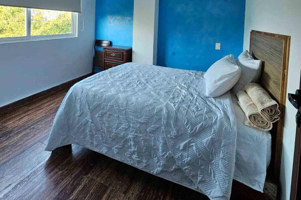 Un dormitorio con una cama grande, cabecera de madera y ventana con vistas a zonas verdes.