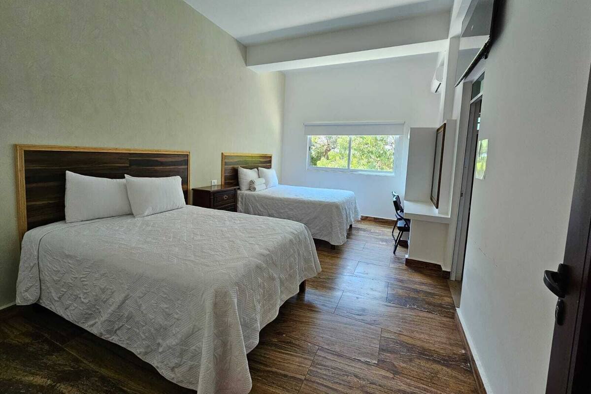 Una habitación de hotel con dos camas, una ventana y una puerta.