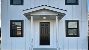 A two-story building with a central entrance, a small porch, and a front door. - The Greenfield: 2-bedroom townhome close to LSU (Baton Rouge)