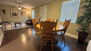 A dining area with a round table and wooden chairs, a ceiling fan, and a potted plant. - The Greenfield: 2-bedroom townhome close to LSU (Baton Rouge)