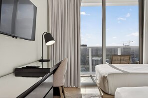 A modern hotel room with a bed, a desk, a chair, a TV, and a large window with a view of the city. - Modern 3BR Condo with Intracoastal View - NO RESORT & PARKING FEE, CHECK DETAILS (Hollywood)