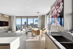 A modern apartment with a kitchen, dining area, and large windows offering city views. - Modern 3BR Condo with Intracoastal & City Views - 25 min to FIFA! (Hollywood)