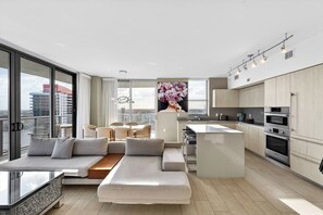 A modern apartment with a living area, kitchen, and large windows offering city views. - Modern 3BR Condo with Intracoastal & City Views - 25 min to FIFA! (Hollywood)
