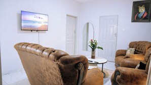 Un salon avec un canapé en cuir, un téléviseur à écran plat et un tableau encadré au mur.