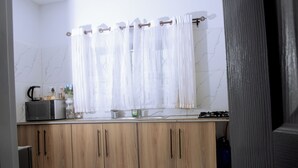Une cuisine avec des meubles en bois, un four à micro-ondes, une bouilloire et une cuisinière à gaz.