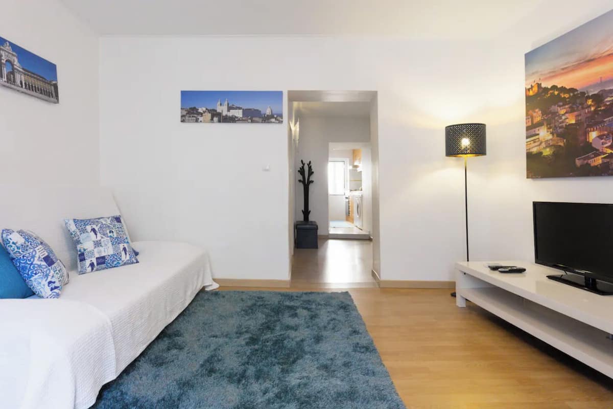 Une chambre moderne avec un lit, un tapis bleu, une télévision et une lampe.