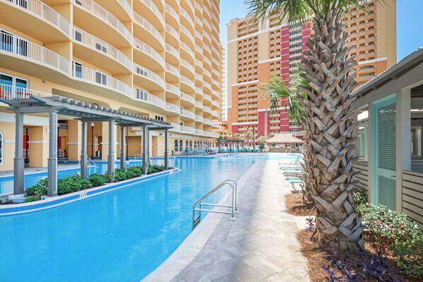 A hotel with a large indoor pool, multiple balconies, and a palm tree.