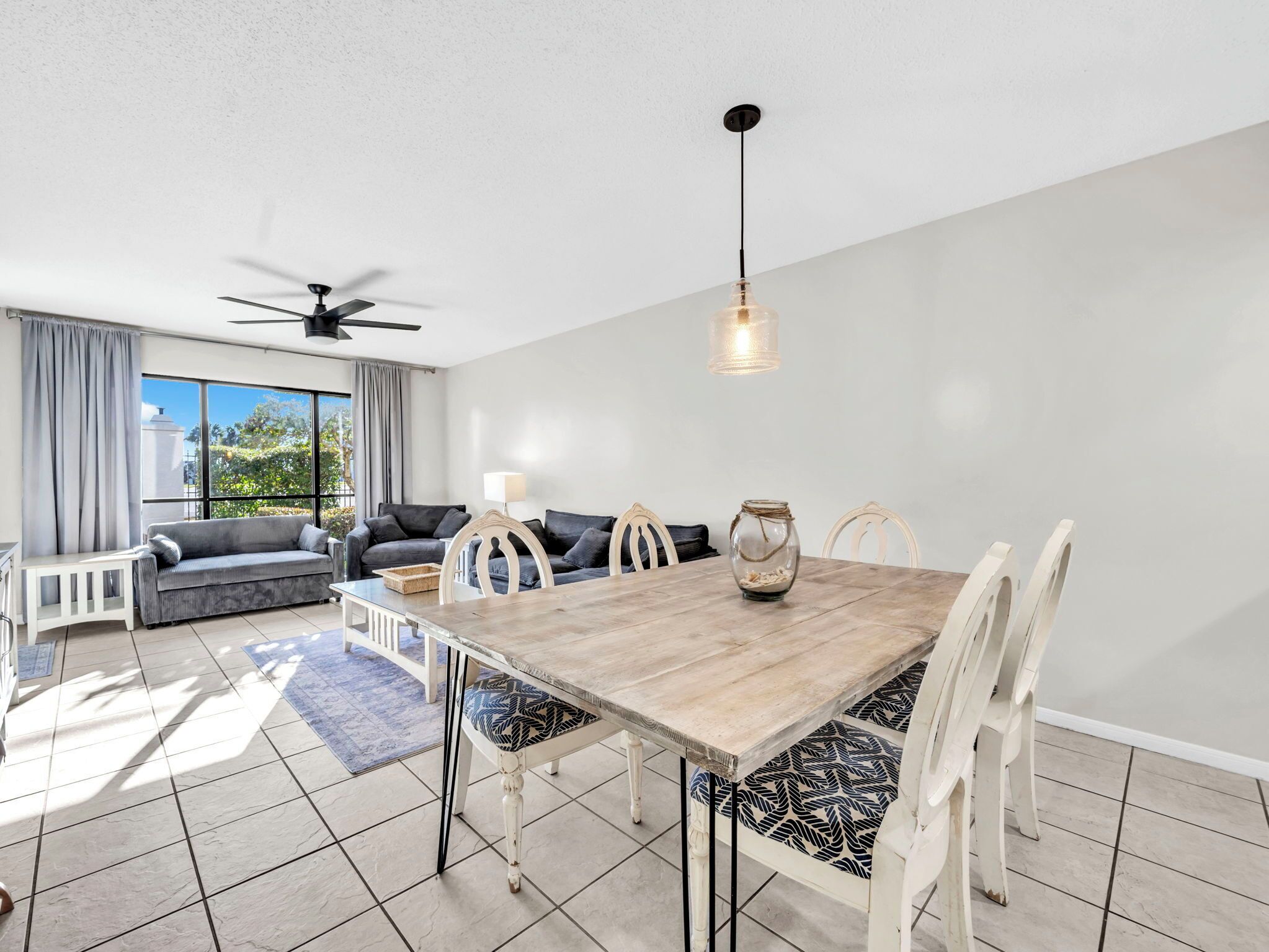 A modern living room with a dining table, sofas, and a ceiling fan.