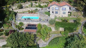 Una casa in pietra a due piani con piscina, pannelli solari e un giardino.