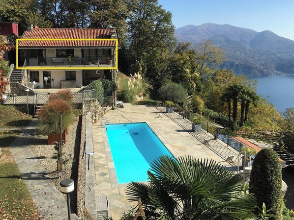 Un bâtiment à deux étages doté d’une piscine, entouré d’arbres et de montagnes.
