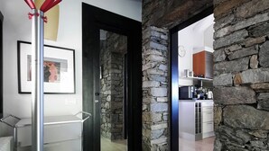 Una cucina moderna con pareti in pietra e soffitto in legno, una foto incorniciata appesa alla parete e un portariviste con maniglie rosse.